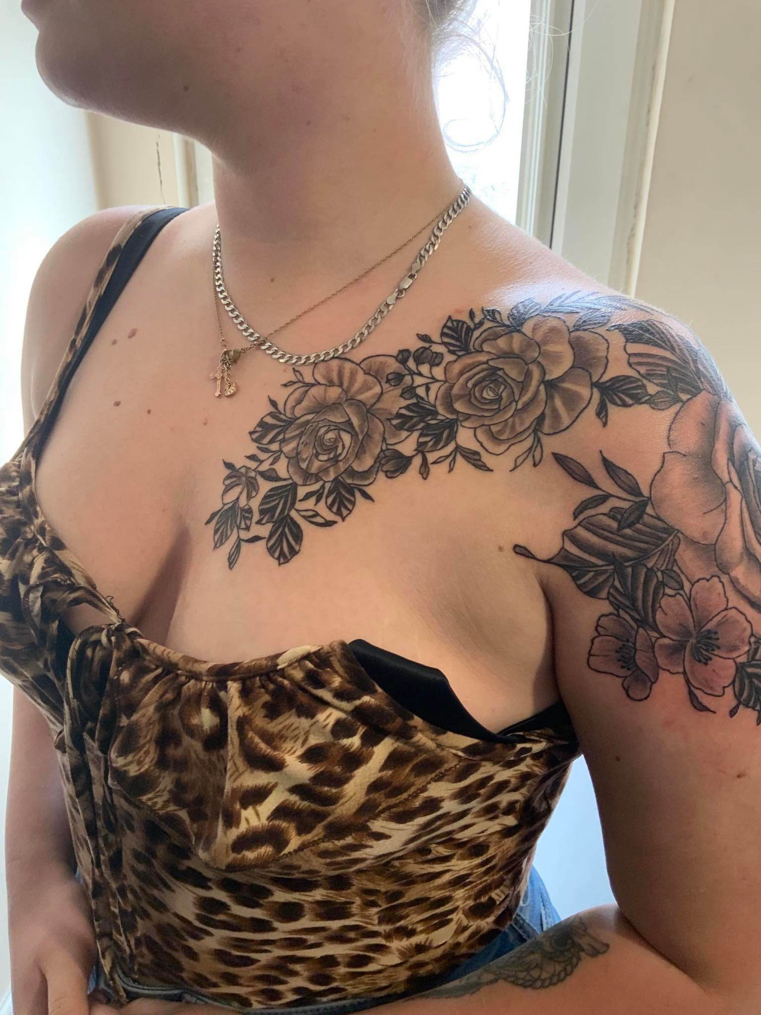 The shoulder of a lady that is covered by a tattoo of flowers
